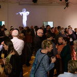 Audience in front of a wall with projected video compilation of past Sundays on Broadway performances at the first ever Gala featuring Meredith Monk - <a href="https://redesign.cathyweis.org/calendar/november-19-2019-glittering-gala-with-meredith-monk" target="outside">November 19, 2019</a> <br/>Photo by Ian Douglas